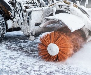 Cleaning snow concept. Tractor clears way after heavy snowfall. Worker ploughs white snow after snowstrom. Snow blowing machine in street